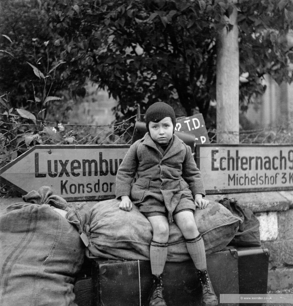 Small tired boy (Raymond Melcher aged 7) waits at cross roads for transport, Iweschtgaass, Bech, Luxembourg
